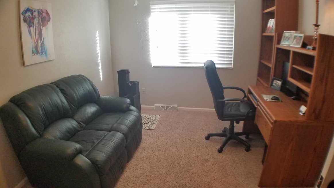 home office room with black sofa, office chair, and table